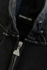 Oversized cropped pigment black hoodie by Alphabet City, heavyweight 500+ GSM 100% cotton with terry inside, double silver A logo zip pullers, drop shoulder fit, cord drawstring with stoppers, and embroidered A logo on sleeve. Unisex design, custom oversized cropped fit, shown on model Jassy wearing size medium. Free All Stars Miami T-shirt included with every order.